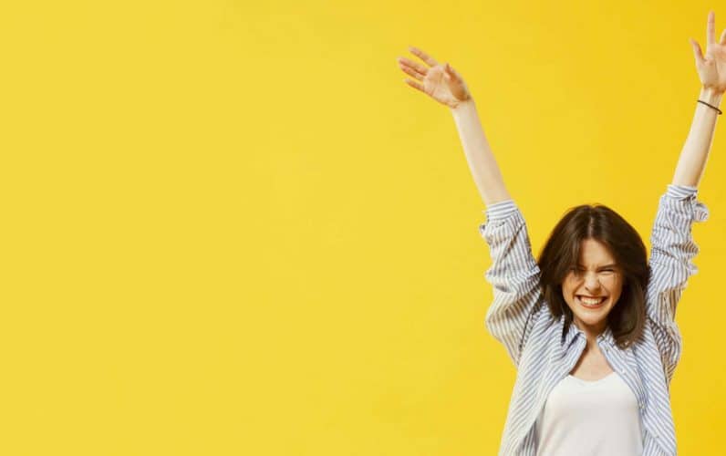 Chica joven contenta estirando los brazos hacia arriba